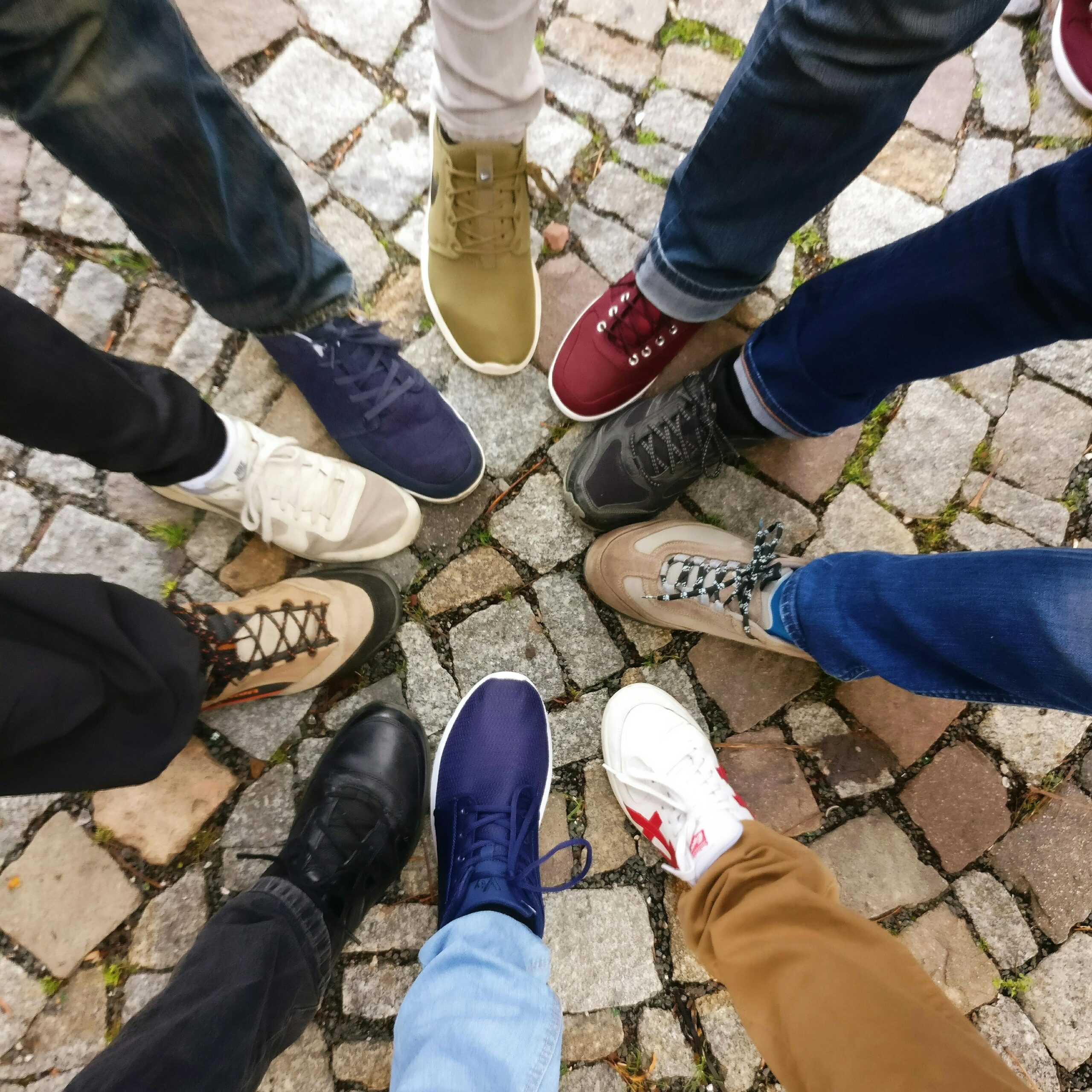 Home Circle of sneakers on cobblestone pavement representing diversity and urban fashion.